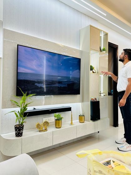 A wide view of a TV unit with a curved console. The design combines a textured back panel with open display shelves, creating a balanced and stylish entertainment center.