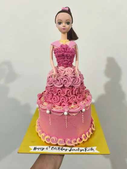 Hi Barbie. This classic doll cake features a real Barbie doll with an elaborate dress made of intricately piped pink buttercream rosettes. It's a dream cake for any Barbie fan.