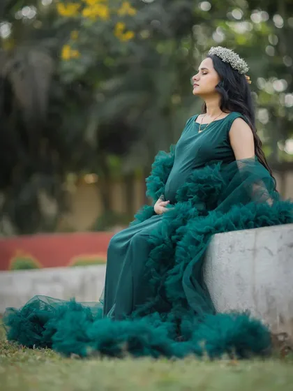 A peaceful, reflective moment captured as the mom-to-be sits serenely in her beautiful green gown.