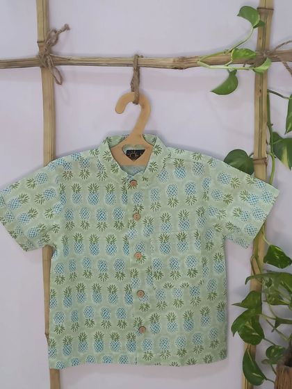 A flat-lay of our pineapple print shirt, showing the wooden buttons and quality stitching. It's a great summer staple for any little boy's wardrobe.