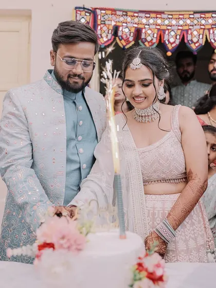Celebrating their engagement with a cake. The bride looks radiant with a soft makeup look and a chic, braided hairstyle.