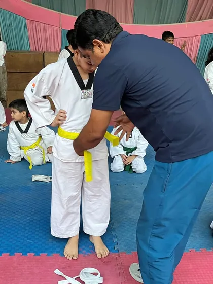 A young student stands proudly as he receives his new yellow belt during our belt promotion ceremony.