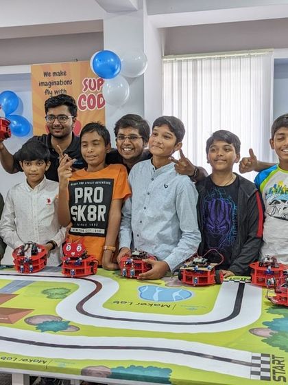 A group of proud students poses with their robots after a successful community meetup. These events often include friendly competitions and project showcases, fostering a spirit of achievement and camaraderie.