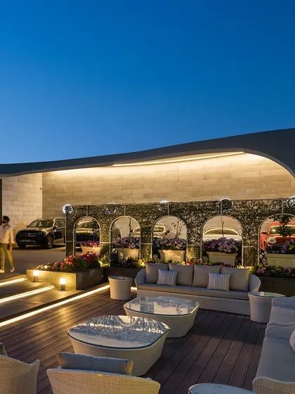Our architectural lighting design transforms spaces as day turns to night. The exterior of this modern event outhouse is illuminated to highlight its unique fluidic curves and create a warm, welcoming glow for evening gatherings, blending the structure with the serene landscape.