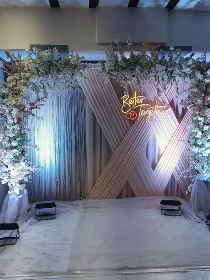 A stylish and textured backdrop for an engagement party. I used a geometric panel design behind sheer curtains, accented with a white floral arch and a "Better Together" neon sign.