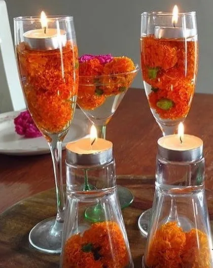 A simple yet elegant centerpiece idea for a festive table. We used champagne and martini glasses filled with marigold petals and floating tea lights, creating a beautiful and unconventional decorative arrangement.