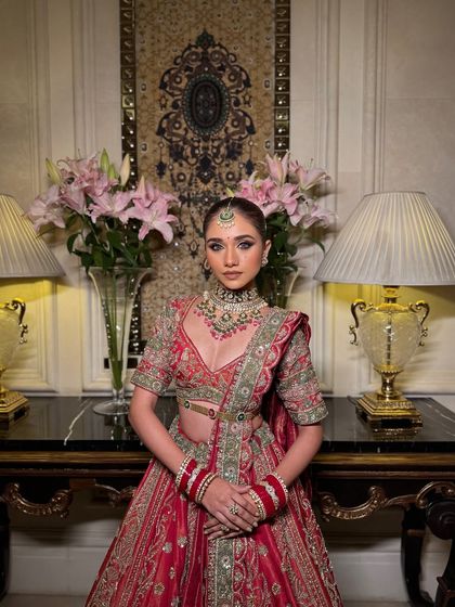 This shot shows the complete look in a real wedding setting. The makeup remains flawless and radiant, complementing the intricate jewellery and the rich colours of her bridal lehenga.