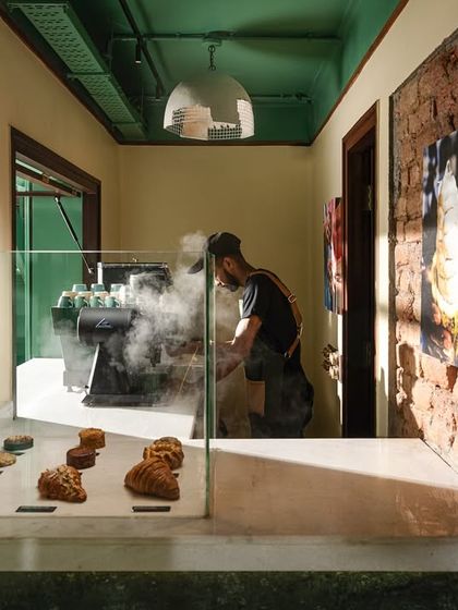 I exposed the original brick walls to ground the space in its history, creating a textural backdrop for the modern coffee bar. This detail shot shows the steam from the espresso machine against the rough brick, a moment where craft and material heritage meet.