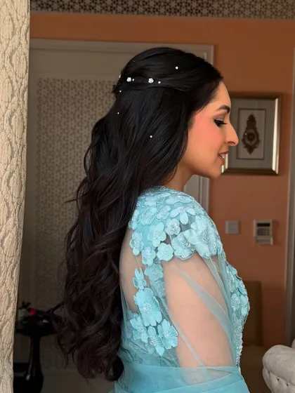 A side view of the pearl-dotted half-up style, showing the soft waves and elegant twist.