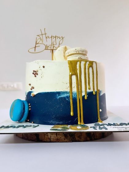 A Fresh Fruit Gateaux designed for a 50th birthday. This cake combines a classic flavour with a modern design, featuring a deep blue and white colour scheme, a gold drip, and macarons.