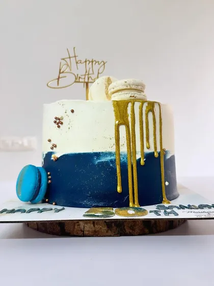 A Fresh Fruit Gateaux designed for a 50th birthday. This cake combines a classic flavour with a modern design, featuring a deep blue and white colour scheme, a gold drip, and macarons.