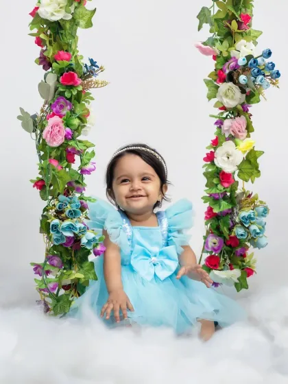 This little girl is so happy and content on her first birthday, surrounded by flowers and clouds.