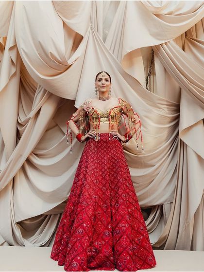 The bride stands tall and confident, her intricate jewelry braid and stunning red lehenga creating a powerful and unforgettable image.