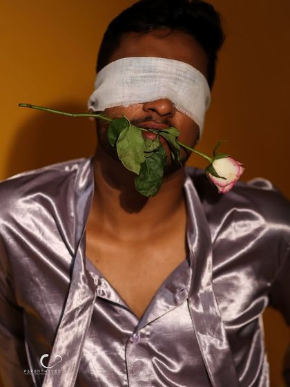 A close-up that focuses on the textures of the rose, the blindfold, and the satin. It's a tactile and visually rich image.