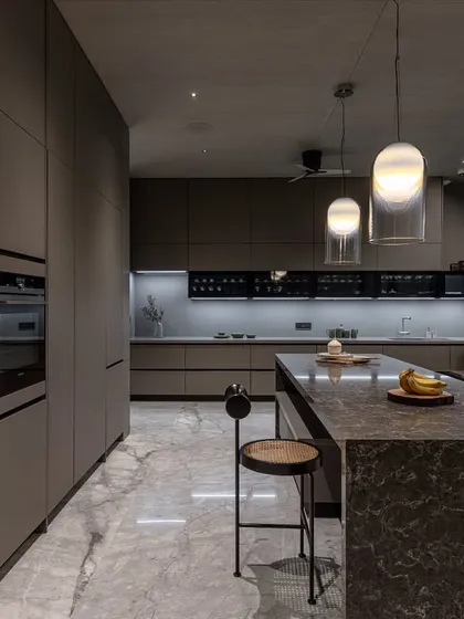 The handleless, floor-to-ceiling cabinets provide immense storage while maintaining a clean, uncluttered look. Integrated shelving offers space for display items.