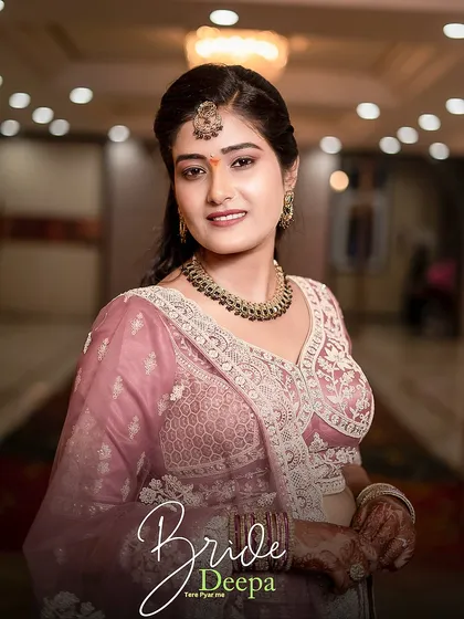 A classic bridal portrait of Deepa, capturing her warm smile and the beautiful details of her necklace and maang tikka.