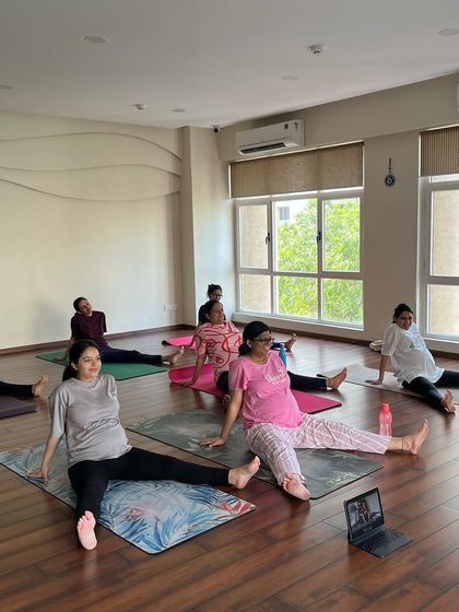 In this class, we explore a seated wide-legged stretch to open the hips and inner thighs. You can also see how we welcome mothers joining online, ensuring everyone can be part of our community.