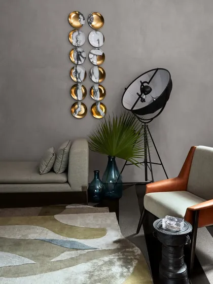 A minimalist seating area in the Baid Residence, featuring a wall piece from Foscarini and a floor lamp from Pallucco. The serene grey palette creates a calm, sophisticated atmosphere.