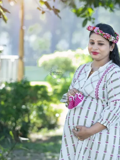 A solo portrait holding tiny pink shoes close to her heart. The floral crown and soft light create a gentle and feminine look for this mom-to-be.
