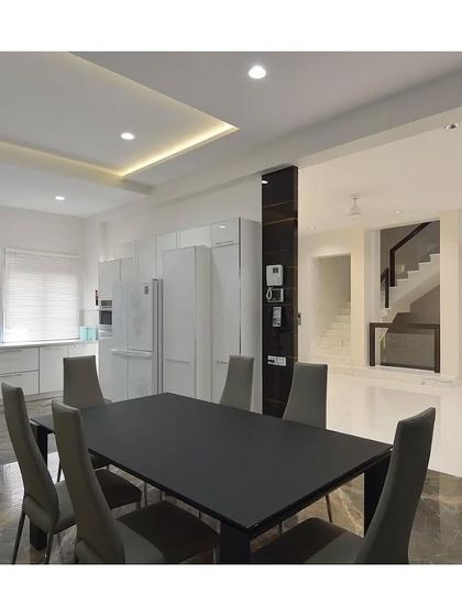 A minimalist dining area where a sleek black table contrasts sharply with the all-white kitchen and glossy floors. This space demonstrates how a simple color palette can create a bold, contemporary statement.