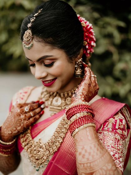A close-up portrait of a bride, capturing the details of her makeup, jewelry, and henna.