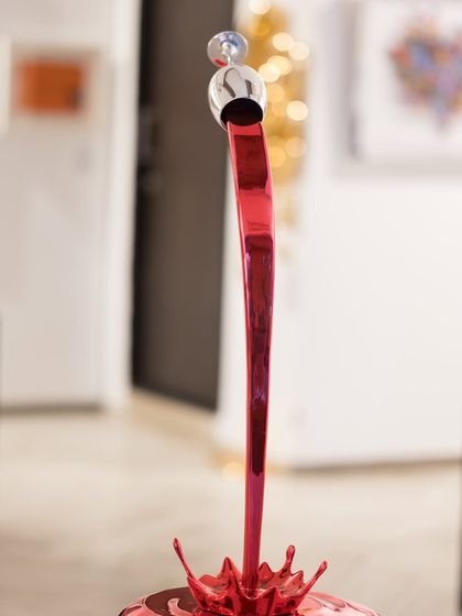 A close-up of the "Gravity Uncorked" sculpture, focusing on the moment the red liquid splashes into the base.