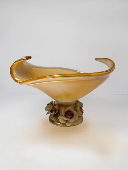 Gracefully perched on a sculpted rose base, this amber-toned Murano vase brings a delicate charm to any space. It is a perfect blend of floral beauty and fine Italian glasswork.