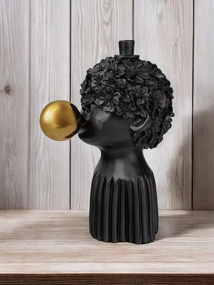 A whimsical and modern showpiece of a figure blowing a golden bubble. The contrast between the matte black finish and the shiny gold sphere makes it a fun and eye-catching piece of art.