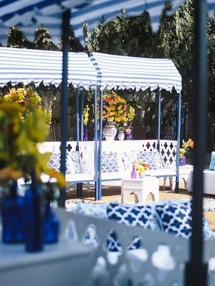 A wider view of the blue and yellow Haldi setup, showing the striped canopies and the fresh, summery vibe created by the color combination. The blue pottery motifs on the cushions tied the whole look together.