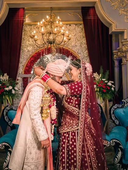 The varmala exchange, a pivotal moment of the wedding ceremony, captured with beautiful, dramatic lighting.