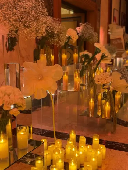 Mirrored pedestals and glass vases filled with candles and flowers reflect the light, amplifying the magical atmosphere.