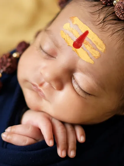 A macro shot of the newborn's face, focusing on the sacred tripundra. These details make the portrait truly special.