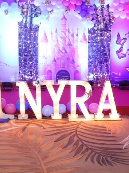 Another precious moment from Nyra's first birthday, showing the scale of the marquee letters and stage setup.