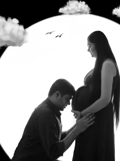 A tender black and white silhouette of a partner connecting with the baby bump. The moon and clouds edit adds a dreamy, protective feel to the moment.