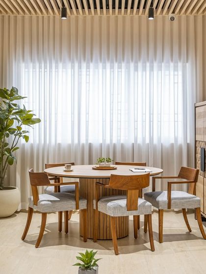 The director's room includes this collaborative meeting table. The round wooden table encourages open discussion, while sheer curtains diffuse natural light, creating a bright and inviting atmosphere for leadership meetings.
