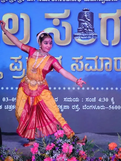 A wide-angle shot of a Bharatanatyam performance, showing the dancer's dynamic pose and the grand scale of the stage.
