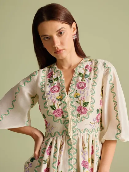 Florals that speak the language of grace. This close-up shows the beautiful, multi-colored floral embroidery on the yoke of this white dress.