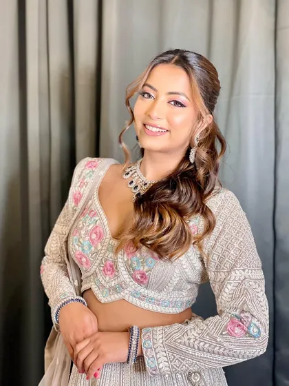 This model smiles brightly, showing off a modern zircon necklace with black stones that perfectly complements her embroidered lehenga. It's a great choice for a contemporary wedding guest look.
