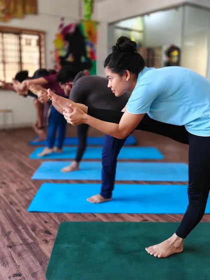 Students practice Ardha Chandrasana (Half Moon Pose) in a line, working on balance and alignment.