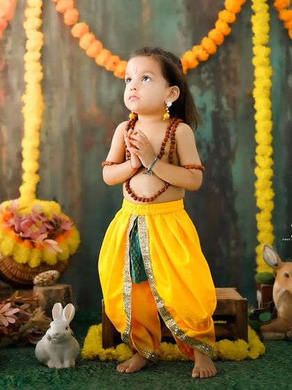 A prayerful pose from the 'Little Ram' session. The child stands with hands together, looking up with innocence and grace in a beautifully composed shot.