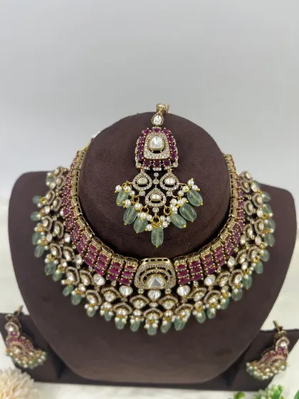 An exceptionally crafted bridal necklace set combining ruby-colored stones with mint-green bead drops. This piece demonstrates our ability to create complex, multi-colored designs with premium Moissanite stones for a rich, designer appeal.