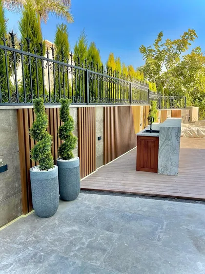 A modern rooftop or patio space featuring composite decking, a wood-slatted privacy screen, and contemporary planters. We use a mix of materials to create a functional and stylish outdoor area.