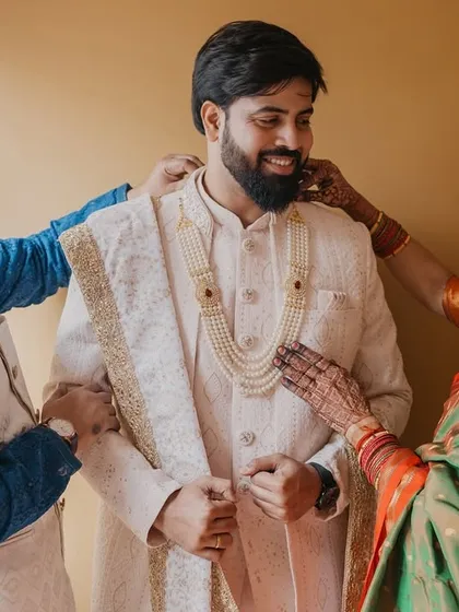 A touching moment as the groom's parents help him get ready, their pride and love evident in their expressions.