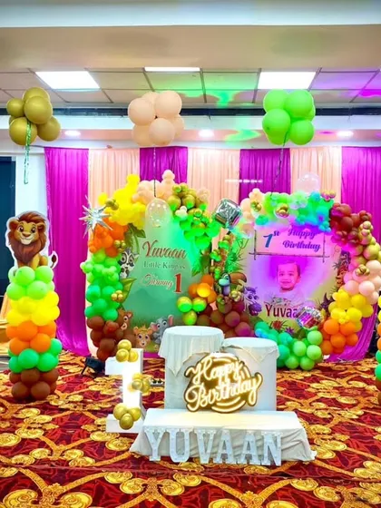 A full view of the jungle-themed stage, complete with animal cutouts, a personalized backdrop, and a "Happy Birthday" light-up sign.