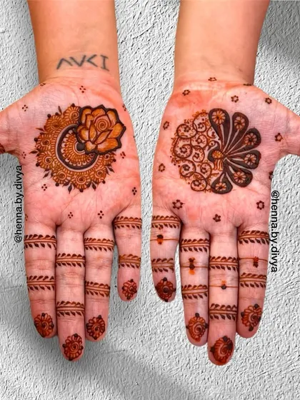 This design shows how two different minimal motifs can create a beautiful, coordinated look. One hand features a lotus and rose mandala, while the other has a stylized peacock fan, both with simple finger details.