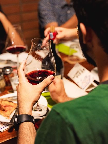 A guest holds up a glass of red wine to the light, appreciating its color and aroma during our curated event.