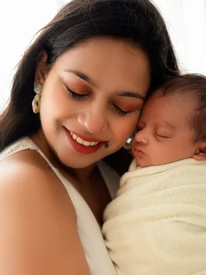 A mother's serene smile as she cuddles her sleeping newborn. A perfect capture of maternal bliss.