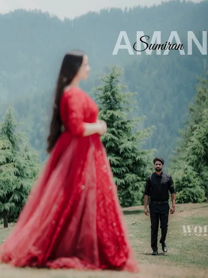 A soft-focus portrait of a couple in a mountain field, with the woman in the foreground and the man walking towards her, creating a dreamy, cinematic feel.