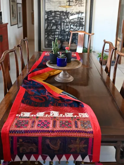 A custom table runner designed to bring life and tradition to the dining space. This piece combines an indigo and madder hand-block printed body with a vintage Banjara embroidery panel, featuring quirky, free-motion embroidered animal figures. It’s a perfect example of how we can blend different craft forms to create something unique for your home.