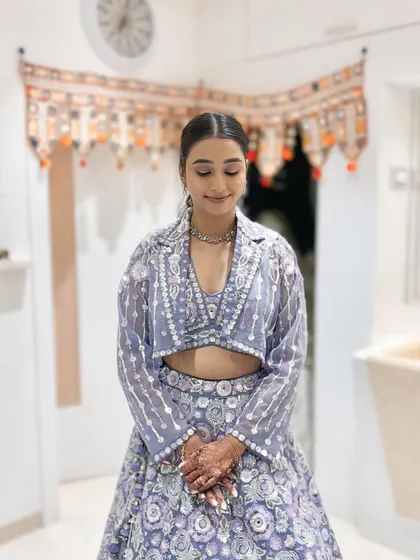 Her sangeet makeup is fresh and modern, with a sleek ponytail that complements the contemporary design of her outfit.